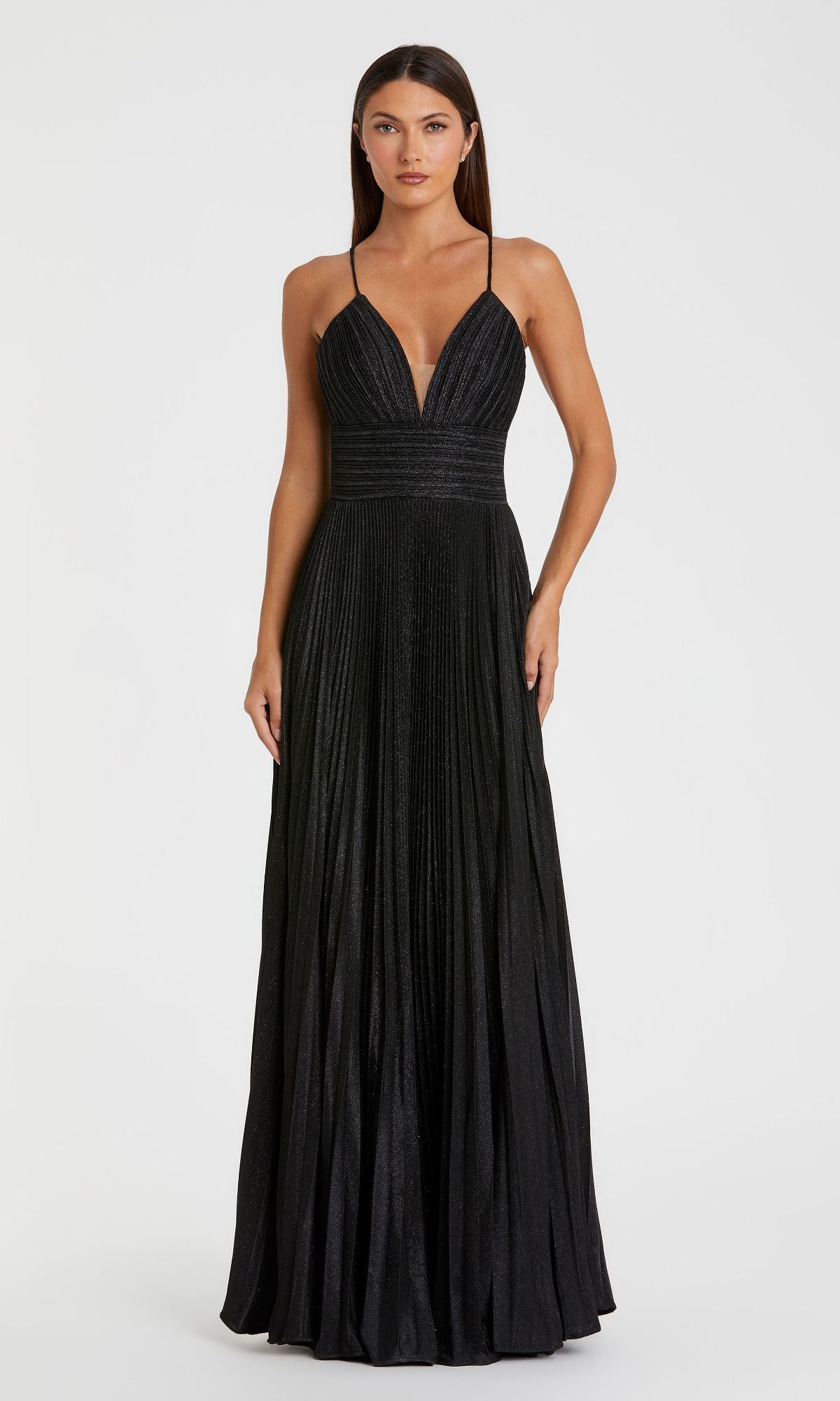 Woman wearing the Pleated Empire-Waist Long A-Line Prom Dress 30725, a sleeveless black gown with a deep V-neckline, thin straps, and pleated skirt, standing against a plain white background.